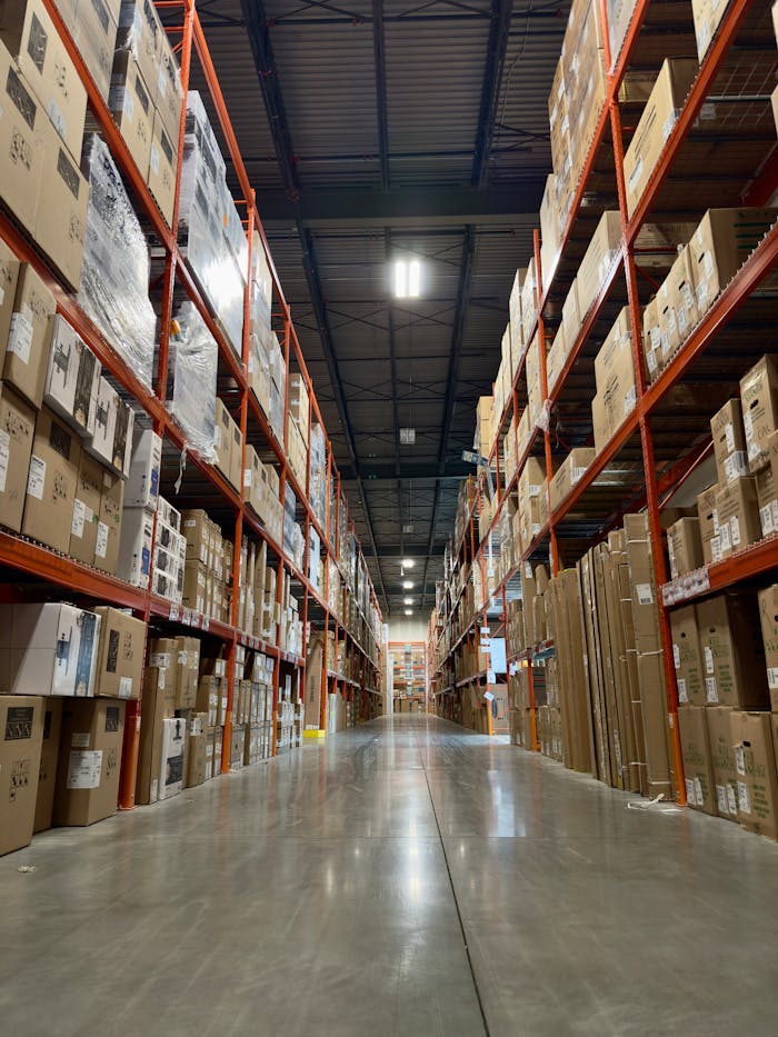 Long aisle in a busy warehouse stacked with boxes and products on shelves.